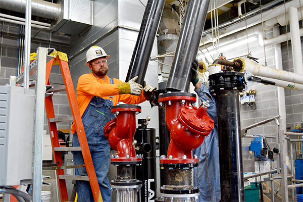technician performing preventative maintenance on piping system