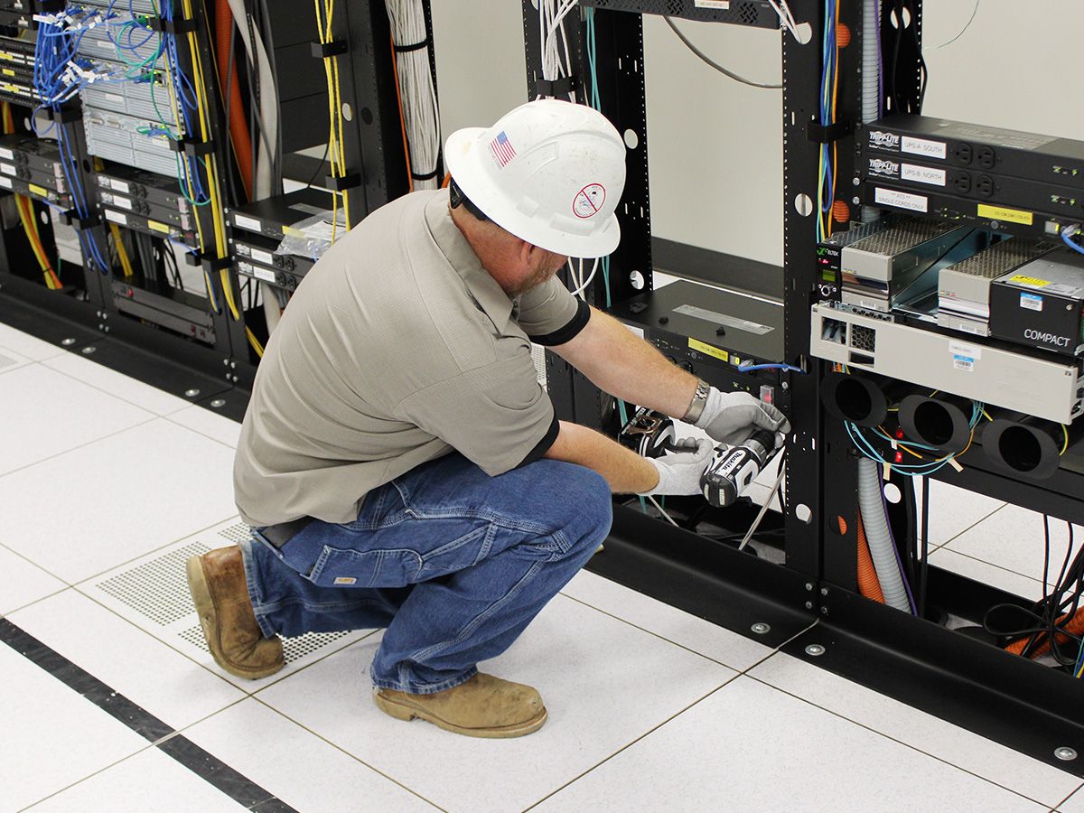 electrician servicing rack mounted electrical equipment