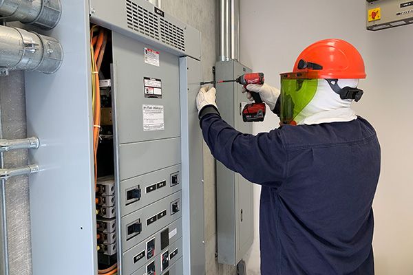 electrician in protective gear repairing electrical panel