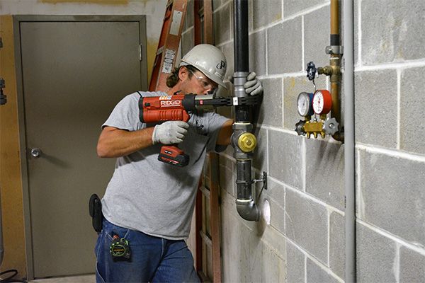 plumber working on pipes with power tools